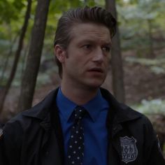 a man wearing a tie and jacket in the woods