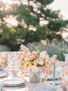 a table set with flowers and candles for an outdoor wedding reception in the sunbeams