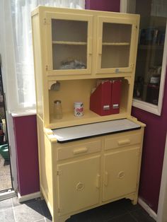 a yellow china cabinet with two red boxes on it's top and bottom shelf