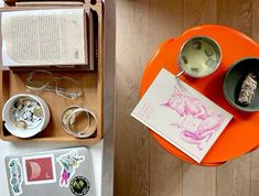 an orange tray with various items on it and a book in the middle next to them