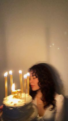 a woman standing in front of a cake with lit candles