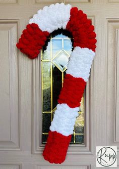 a red and white christmas wreath hanging on the front door