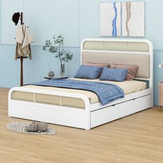 a white bed sitting on top of a hard wood floor next to a blue wall