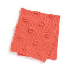 an orange crocheted dishcloth with small flowers on the edges and two rows of holes in the middle