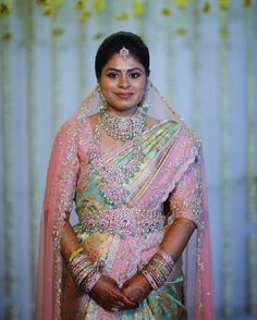 a woman in a pink and green bridal outfit posing for the camera with her hands on her hips