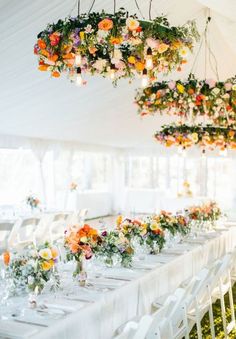 the tables are set with white linens and floral centerpieces hanging from the ceiling