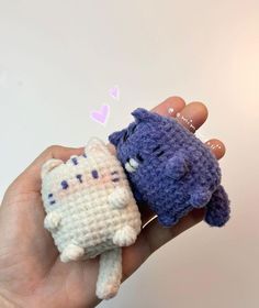 two small crocheted cats are held in the palm of someone's hand