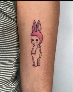 a person with a tattoo on their arm and the image of a rabbit wearing a pink hat