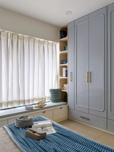 a bed room with a neatly made bed next to a window and some cupboards