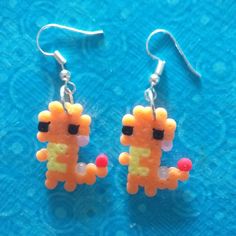 a pair of earrings made to look like an orange and yellow cat sitting on top of a blue surface