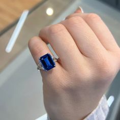 a woman's hand with a ring on it and a blue stone in the middle