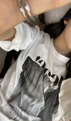 a woman laying on top of a couch wearing a white shirt and silver bracelets