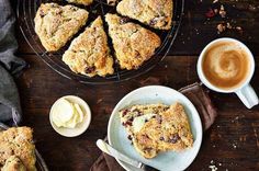 scones with raisins and other toppings sit on a table next to a cup of coffee