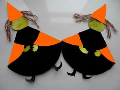 two paper witches with orange hats on their heads and legs, one wearing a black dress