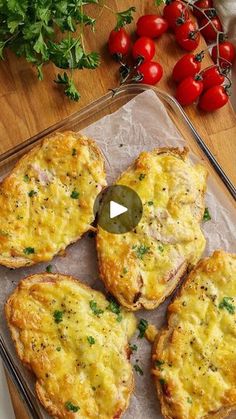 four cheesy breads on a baking sheet with tomatoes and herbs in the background