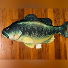 a large fish shaped pillow sitting on top of a wooden floor next to a wall