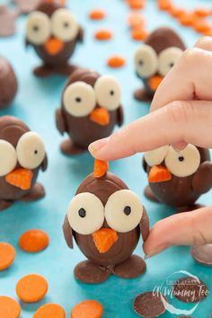 a hand is picking up some candy from a table with chocolate penguins and carrots