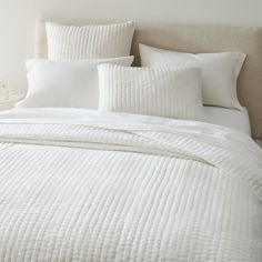 a bed with white sheets and pillows on top of it