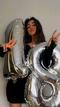 a woman holding two large silver balloons in front of her face