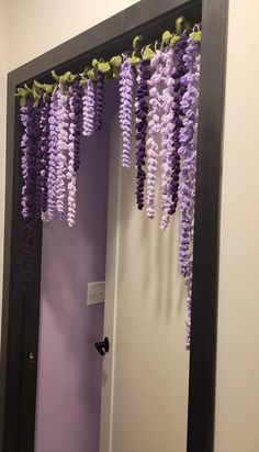 purple flowers are hanging from the ceiling in front of a mirror that is decorated with black trim