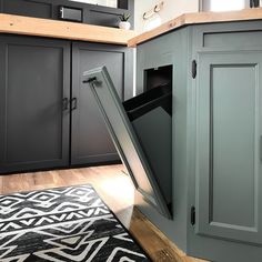 an open cabinet door in the middle of a kitchen with a rug on the floor