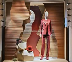 a mannequin dressed in a red suit and hat next to a window display