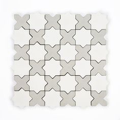 a white and grey tile pattern on the wall, with small gray stars in the middle