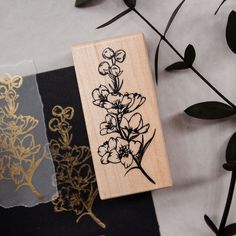 a rubber stamp with flowers on it sitting next to some paper and plants in the background