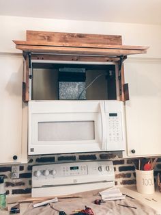 a microwave oven built into the side of a kitchen wall with wood trimming around it