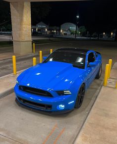 a blue mustang parked in a parking lot at night