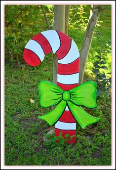 a wooden candy cane with a green bow on it's side in the grass