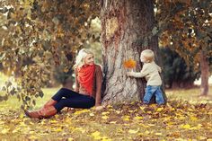 two children are sitting next to a tree