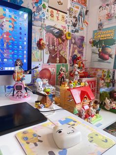 a computer monitor sitting on top of a desk next to a bunch of toy figurines