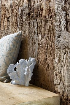 a pillow sitting on top of a wooden bench next to a tree trunk wall covered in bark