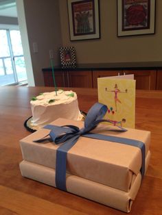 a birthday cake wrapped in brown paper and tied with blue ribbon on a wooden table