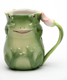 a green frog mug with a pink flower in it's mouth