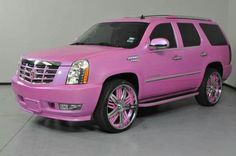 a pink suv with chrome rims parked in a garage next to a white wall