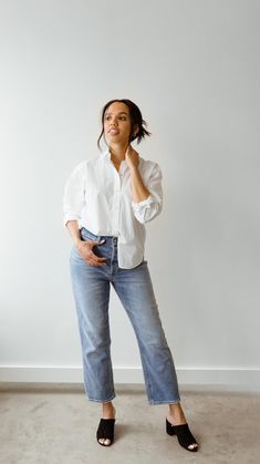 a woman standing in front of a white wall with her hands on her chins