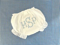 a blue and white checkered table cloth with an embroidered monogrammed diaper