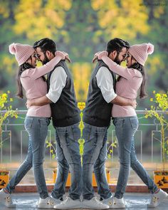 two people hugging each other while standing in front of a fence with trees behind them