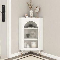 a white cabinet sitting in the corner of a room next to a wall mounted clock