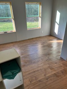 an empty room with wood floors and three windows