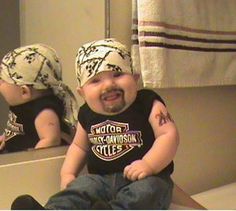 a baby sitting on top of a counter in front of a mirror wearing a bandana