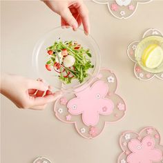 two hands reaching for a salad in a bowl on a table with other plates and utensils