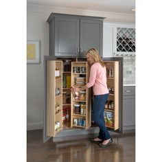 a woman is opening the door to an open refrigerator in a kitchen with gray cabinets