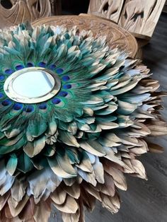 a peacock feather centerpiece sitting on top of a wooden table next to other chairs