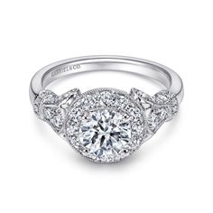 a white gold engagement ring with an intricate halo setting and round diamonds on the band