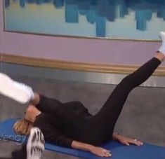 a woman is doing exercises on a blue mat in front of a tv screen with her feet up