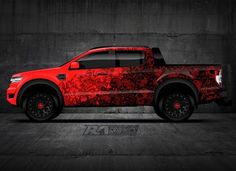 a red pick up truck with black rims on it's tires is parked in a dark room