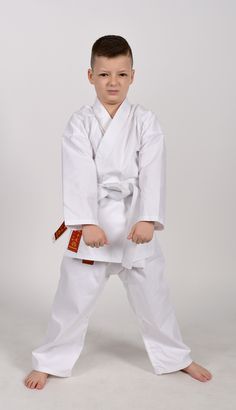 a young boy in white karate gear posing for the camera with his hands on his hips